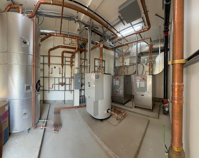 Completed SSW mechanical room with copper piping, water heaters, and insulated storage tanks